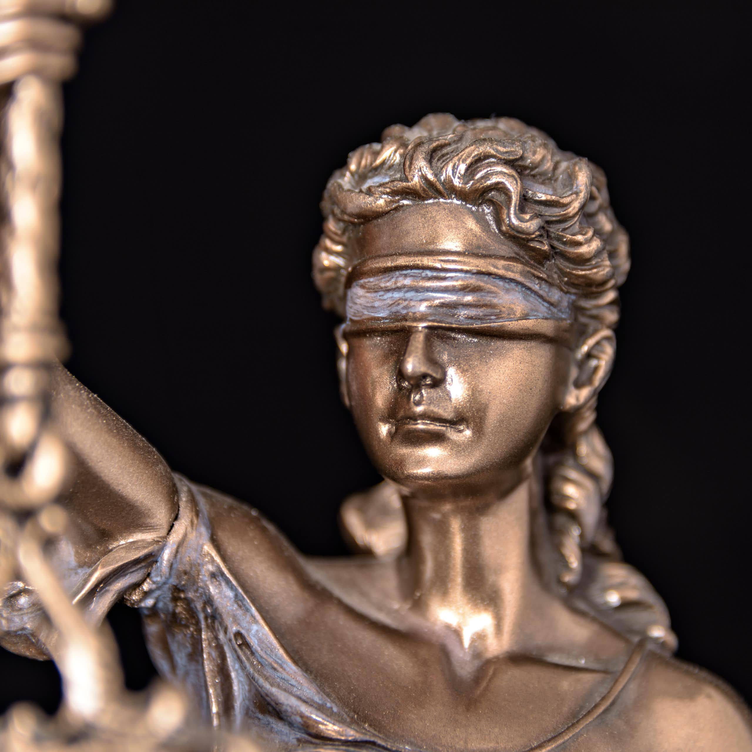 Close-up of a bronze figurine of Lady Justice wearing a blindfold.